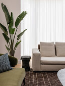 Polstermöbel, Beistelltisch und Zimmerpflanze vor Terrassentür mit bodenlangem Vorhang
