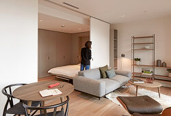 Woman moving flexible partition wall in studio apartment