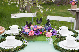 Table festively set for afternoon coffee with luxuriant Easter flower arrangement