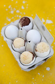 Cakes baked in egg shells in egg box on yellow surface