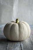 A small white pumpkin on a wooden surface
