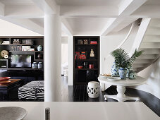 View over kitchen counter on round table, staircase and shelf cabinet