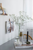 Glass vase and candlestick on grey dining table next to leather magazine holders on wall