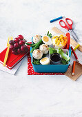 Bento Box mit Avocado-Sesam-Reisbällchen und Joghurt mit exotischen Früchten