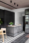 Concrete kitchen island in front of black built-in kitchen