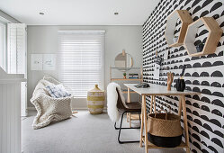 Black and white wallpaper, desk, chair and blanket on armchair in study