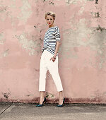 a young blonde woman wearing a stripped shirt, white trousers and snakeskin shoes