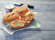 A spelt roll with salmon on sandwich paper