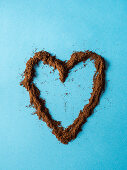 Heart made with grinded coffee powder over blue background