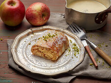 Apple strudel on a pewter plate with vanilla sauce
