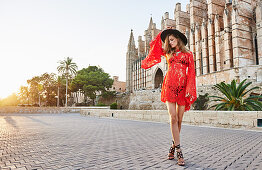 A young woman wearing a black hat and red lace dress