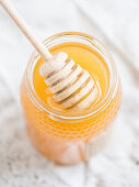A jar of Portuguese honey with a honey dipper (close-up)