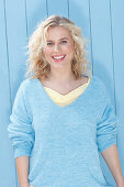 A young blonde woman wearing a blue jumper over a yellow top