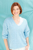 A red-haired woman wearing a blue jumper over a white top