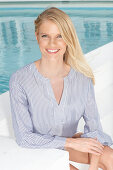 Junge blonde Frau in gestreifter Bluse am Pool