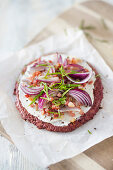 Low-carb tart flambée with a beetroot and sunflower seed base, sour cream, bacon and onions