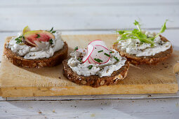 Wholemeal bread topped with herb cream cheese, vegetables and herbs (vegan)