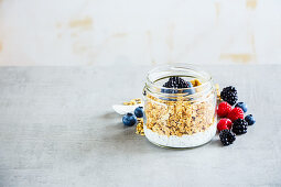 Tasty breakfast in jar, Greek yogurt, granola, fresh berry breakfast, white wooden wall background