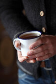 A person holding an enamel mug of tea