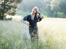 Junge blonde Frau in Lederjacke und Rock im Gras stehend