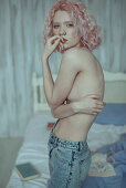 Portrait of pensive topless Caucasian woman in bedroom