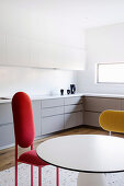 Round table and designer chairs in white fitted kitchen