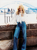 A blonde woman wearing a white pussy bow blouse and jeans