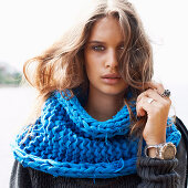 A young woman wearing a blue loop scarf