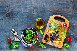 Fresh healthy salad with tomatoes in vintage bowl over rustic wooden background
