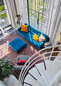 View down onto bright blue sofa and ottoman in double-height, open-plan interior