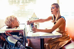 A blonde woman and a little boy dressed as a robot in a restaurant