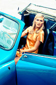 A blonde woman in a blue cabrio