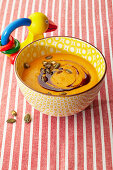 Pumpkin soup with oil and seeds in a bowl next to a baby rattle