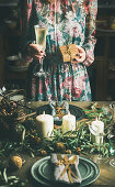 Festlich gekleidete Frau steht mit Sektglas und Geschenk vor weihnachtlich gedecktem Tisch