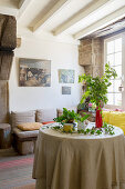 Arrangement of plants on round table in front of bench with cushions