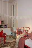 Fairy lights on red metal bed in child's bedroom with patterned floor