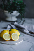 Frische Zitronen, ganz und halbiert auf Schneidebrett