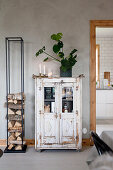 Old glass-fronted cabinet next to modern firewood rack