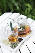 Herbal tea against nausea in a glass teapot and a glass cup