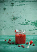 Cornelian cherry jam in a storage jar with a spoon