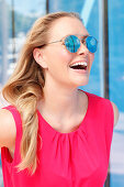 Blonde Frau in pinkfarbenem Top mit Sonnenbrille