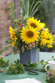 Strauß aus Sonnenblumen und Zieräpfeln in Filztasche