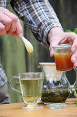 A man adding honey to peppermint tea