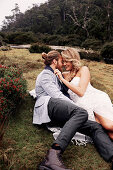 A bride and groom lying in a meadow