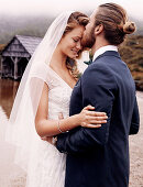 A bride wearing a white dress with a veil and a groom wearing a dark blue suit