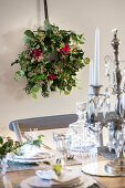 Handmade Christmas wreath with roses on wall behind festively set table