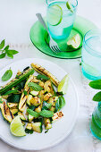 A plate with grilled zucchini, mint leaves and lime wedges