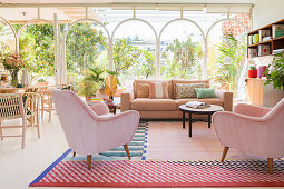 Wohnzimmer in Pastellfarben mit Glaswand zum mediterranen Garten