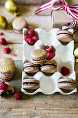 Festive chocolate macarons with gold dust in white holder with raspberries
