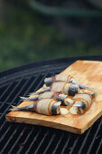 Stuffed herrings wrapped in bacon on a grill